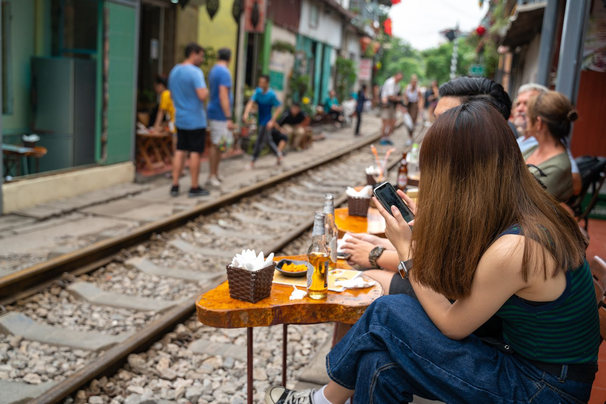 Tourists enjoying coffee at a cafe with a view of Hanoi Train Street tracks